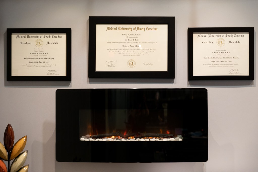 Large image of in-wall fireplace with plaques on wall in office.