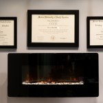 Large image of in-wall fireplace with plaques on wall in office.